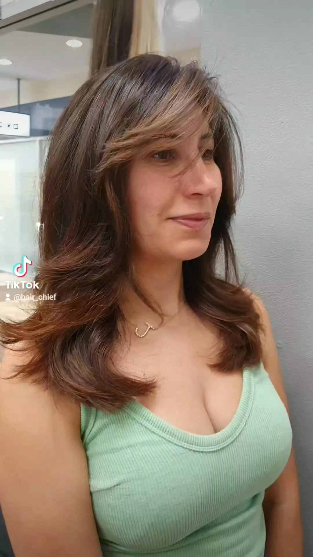 Layered brunette blow-dry with caramel highlights, salon interior with downlights