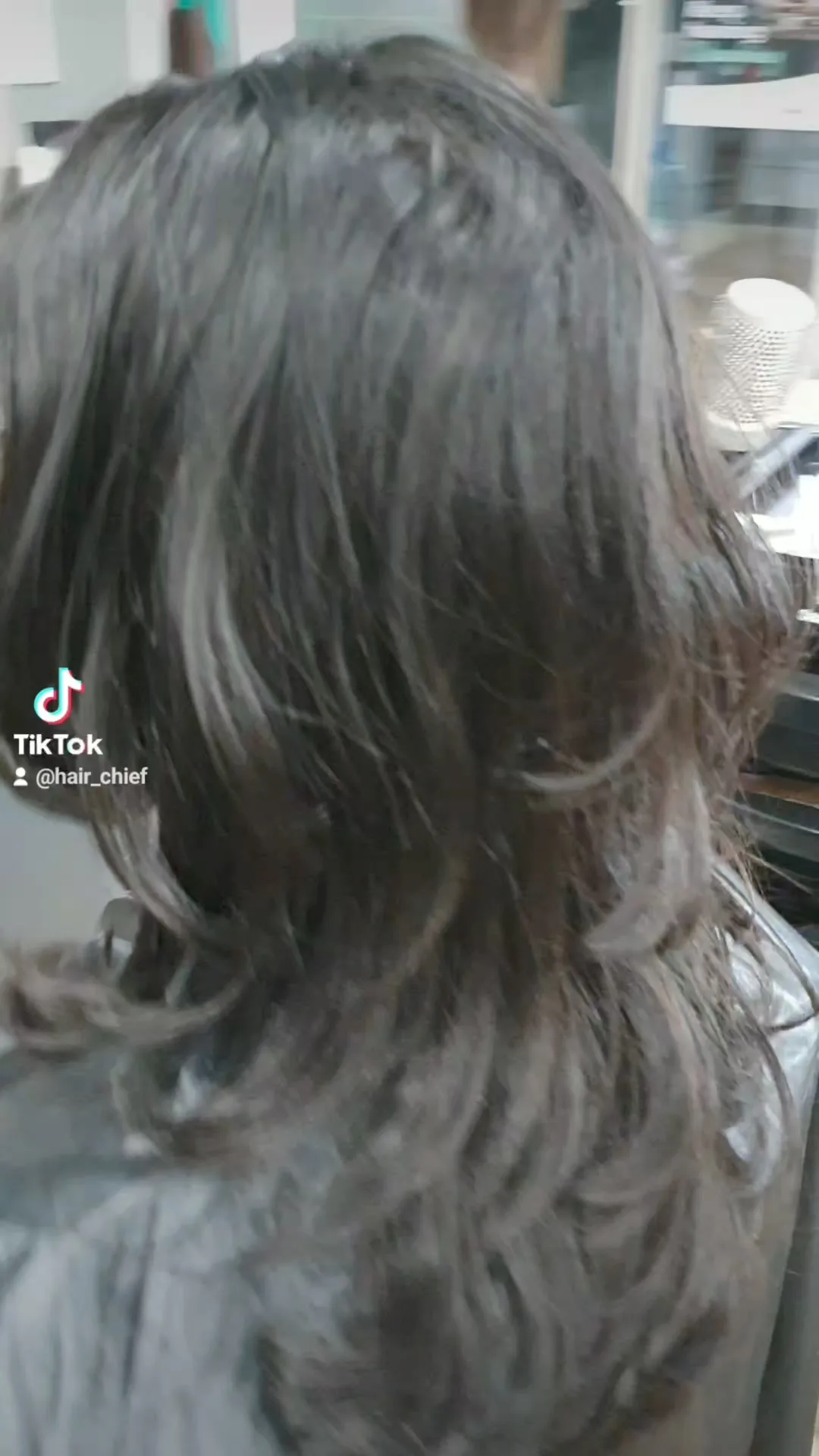Dark hair with ash highlights mid-process, salon equipment in background