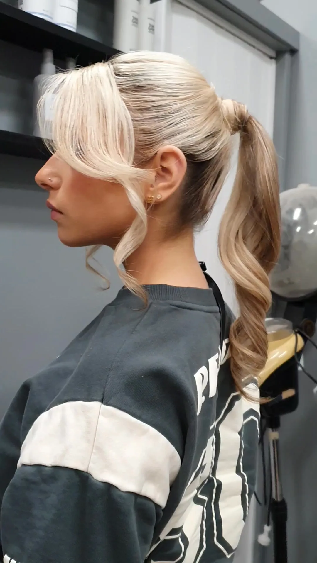 Platinum high ponytail up-style in the salon, product shelves and studio in background
