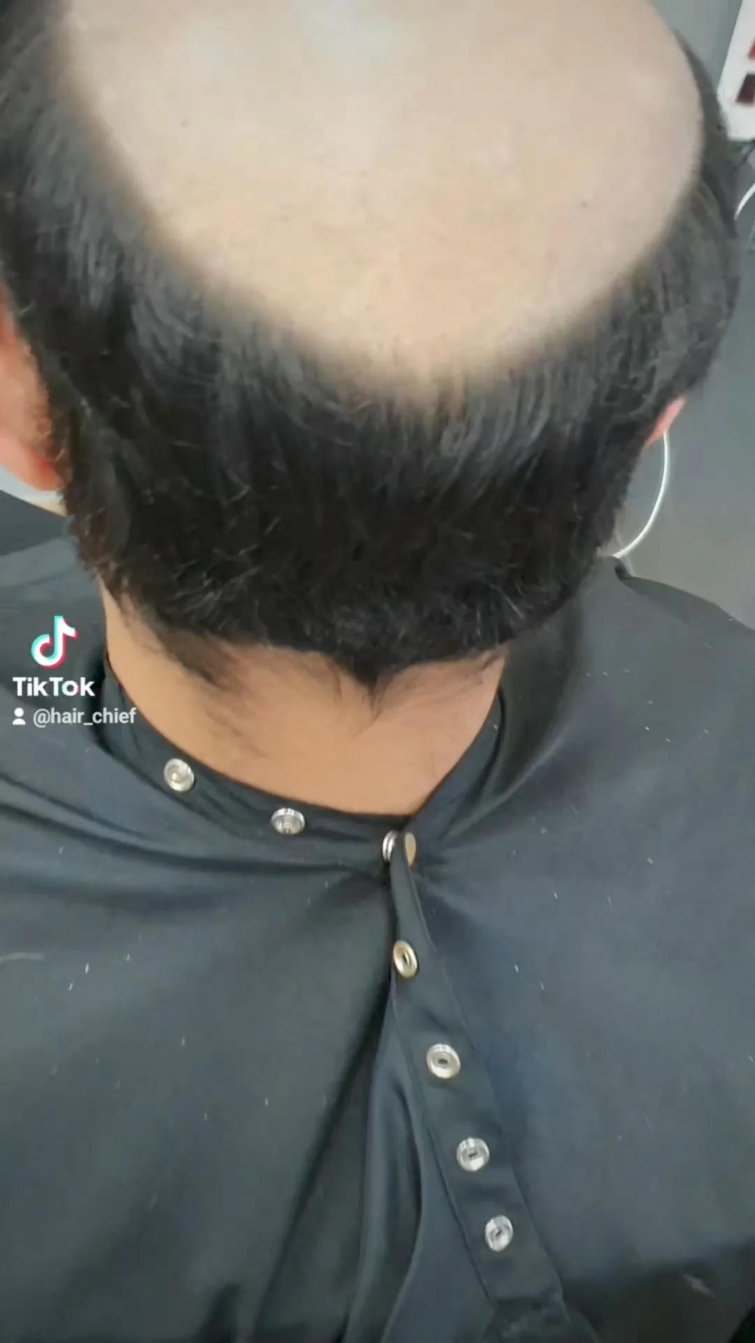 Men's grooming — top-down view of dark crown and nape, cape