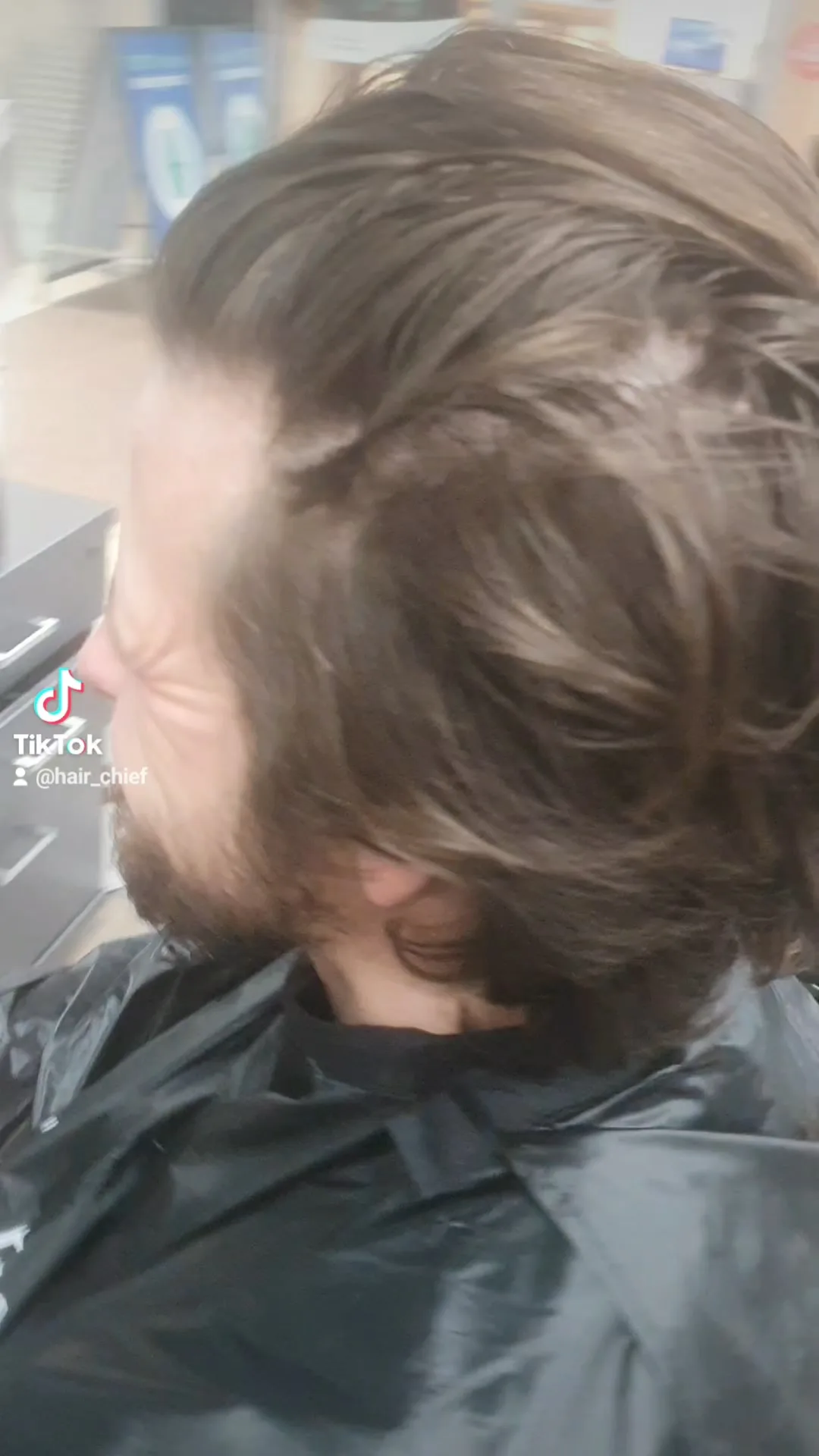 Men's cut — side profile, brown wavy hair and beard, cape