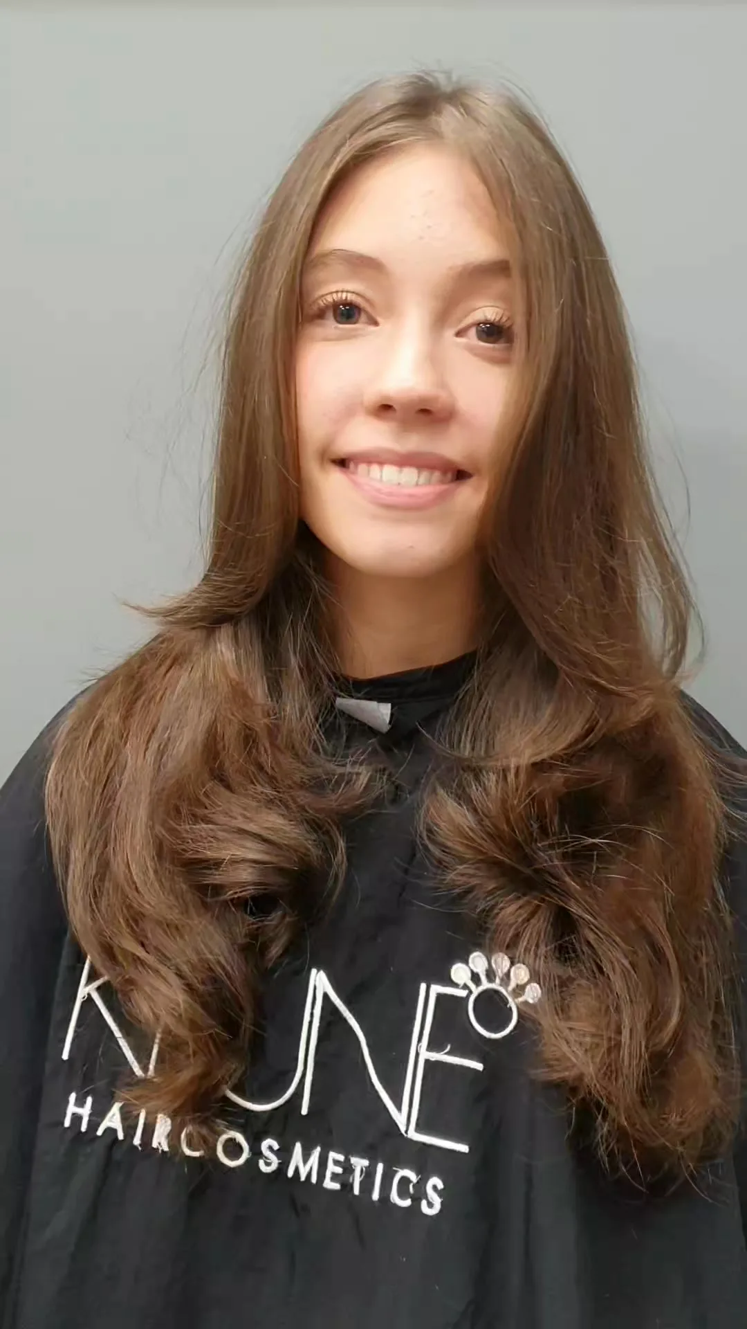 Long glossy brunette waves, smiling client, Keune cape
