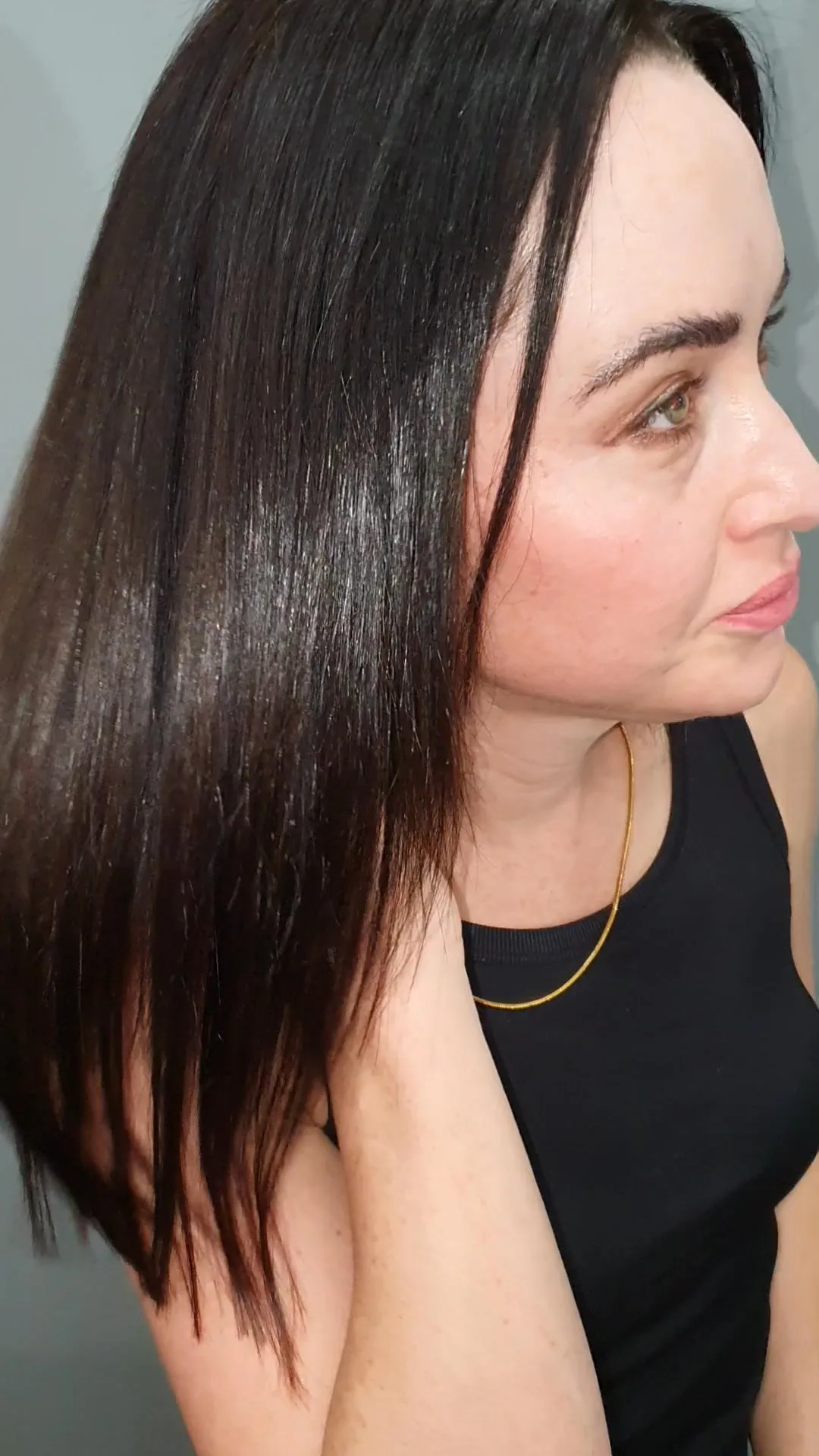 Sleek dark hair with red undertone, side profile, black tank