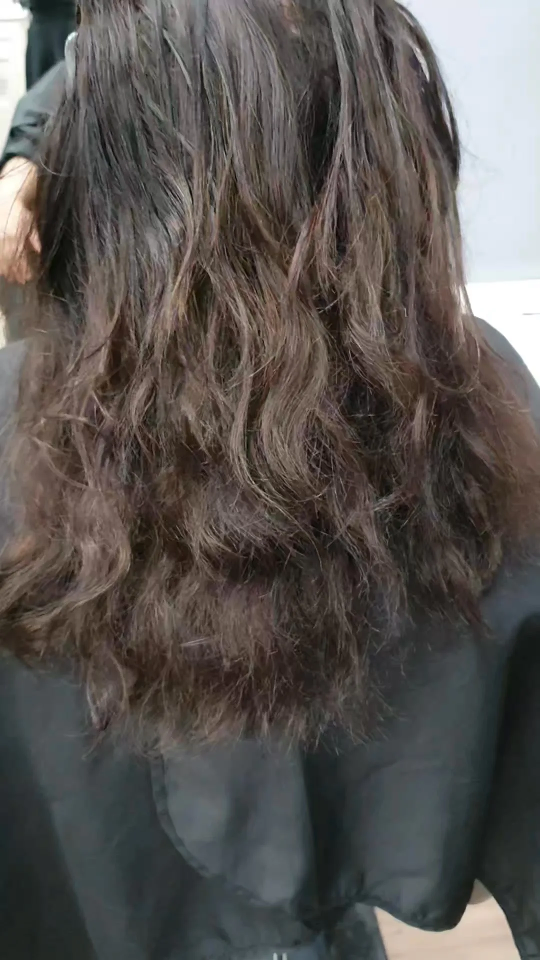 Long dark wavy hair pre-styling, black cape, salon